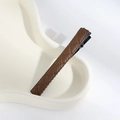 Macro shot of brown quilted PU leather hair clip on a minimalist off-white tray - Snap Clip Coffee