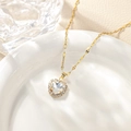 Macro shot of heart-shaped zircon pendant with gold chain on elegant ceramic tray - April-White