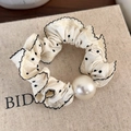 Close-up of vintage polka dot hair scrunchie with ruffle edges and a large pearl - White with Black Polka Dots