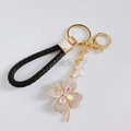 Detail of gold clover keychain with black leather loop and rhinestone crystal beads - Heart Strap / White