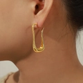 Minimalist gold U-shaped curved earrings with a sleek polished finish on model - Gold
