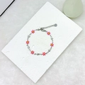 Close-up of pink daisy and silver star charms on an 18k gold-plated stainless steel bracelet - Pink Silver