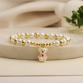 Gros plan d'un bracelet en perles avec un pendentif ours mignon et des perles dorées - Ours Beige en Haut Rose
