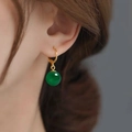 Close-up van gouden oorringen met een groene agaat bolvormige hanger bij een vrouwelijk model - Gouden Groene Agaat