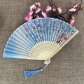 Blue folding fan with pink cherry blossom pattern and blue tassel on linen background - No.60 Blue Cherry Blossom