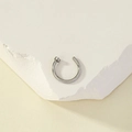 Detailed macro view of silver stainless steel C-shaped nose ring on white textured stone - Lip Ring / Silver