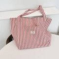 Detailed close-up of a large red and white striped canvas tote bag with a woven label - Burgundy Stripes