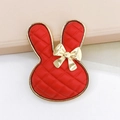 Detailed macro view of a red cartoon rabbit charm with gold bow and lattice texture - Red