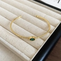 Detalle de brazalete abierto bañado en oro 18k con piedra verde y texturas vintage - Estilo Gema Verde Texturizada Dorada