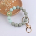 Détail macro d'un porte-clés bracelet en perles de silicone avec breloque marguerite - Marguerite Vert d'Eau