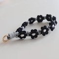Macro shot of hand-woven daisy lanyard with black, grey, white yarn and metal clasp - Black