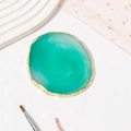 Detailed view of teal resin agate palette with gold electroplated edge on elegant fabric - Green