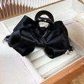 Détail de pince à cheveux en satin noir avec strass dans un coffret à bijoux en velours beige - Pince à cheveux noire