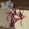 Flat lay of leopard print bikini with red trim ties on textured beach towel and mat - S / Red Leopard