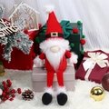 Charming red Christmas gnome figurine sitting on gift boxes with winter holiday decor - Faceless Santa Style