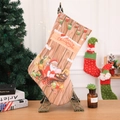 Detailed view of a Christmas stocking with Santa Claus motif on a decorative wooden stand - Beige Santa Gift Bag Style