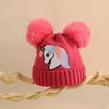 Detail der Kinder-Strickmütze in Rosa mit Bommeln und Einhorn-Stickerei auf Holzständer - Einheitsgröße (2-6 Jahre) / Rosarot