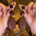 Dettaglio di orecchini vintage in legno con pendente a goccia marrone tenuti in mano - Stile Ovale (HE29559) / caffè