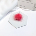 Detail shot of a soft pink mink fur pompom accessory on a white hexagonal base - Pink