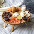 Close-up of a circular wooden folding picnic table with wine glass slots on a soft rug - Small 24x24x11