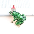 Squisita spilla a corona di rana dorata con smalto verde e cristalli scintillanti - Rana Seduta con Corona