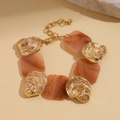Detail von goldfarbenem strukturiertem Metall und braunen Harz-Gliedern am Armband - Armband - Gold