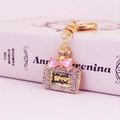 Golden perfume bottle keychain with pink bow and crystal inlay on a pink background - Pink