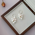 Detail view of cluster pearl drop earrings with silver finish on a wooden jewelry box - Natural White