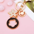Golden flower keychain with LOVE FOREVER disc and black enamel charm on pink background - Black Five-leaf Clover