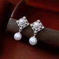 Macro shot of silver pearl earrings with hollow diamond shape and zircon accents - Silver & White (Silver Earring Post)