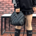 Black woven leather bucket bag with V-shaped handle and thin shoulder strap carried by a model - Black