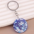 Detail of floral acrylic keychain with blue white pattern on wavy display stand - Blue