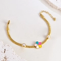 Goldenes Armband mit buntem Emaille-Blütenanhänger und weißen Perlen auf weißem Grund - Breites Armband