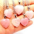 Close-up of pink heart-shaped crystal necklaces with silver chains held in hand - Heart Rose Quartz