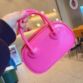 Detail der rosapinken Jelly-Handtasche mit glänzender PVC-Textur und Herz-Griffhalterungen - Rosenrot