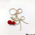 Golden keychain featuring a red cherry pendant and an elegant metallic bow charm - Red Cherry with Gold Bow (Cherry W)