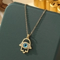 Golden Hamsa Hand necklace with blue Evil Eye pendant on a green jewelry box - A13-Gold