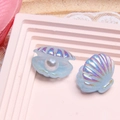 Detailansicht irisierender blauer Harzmuscheln mit weißer Perle auf rosa Display - Himmelblau