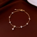 Elegante pulsera de trébol bañada en oro con circonitas blancas sobre seda marrón - Dorado