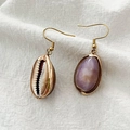 Bohemian schelp oorbellen met gouden metalen randen op een natuurlijke stoffen achtergrond - Schelp Stijl
