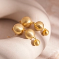 Dettaglio ravvicinato di orecchini pendenti a sfera in metallo dorato opaco dal design geometrico - Gancio per Orecchie a Sfera Dorata / Oro