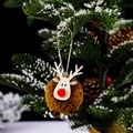 Brown wool ball reindeer Christmas ornament hanging on a snowy pine branch - Brown