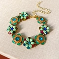 Dettaglio di un bracciale vintage dorato con fiori in smalto colorato e piccoli strass - Bracciale di Fiori (Bracciale-Oro-Verde)