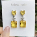 Elegant silver earrings featuring yellow heart and emerald cut stones on a display card - Yellow Diamond Sparkling Earrings Led-123