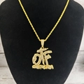 Vue rapprochée du pendentif hip hop doré orné de cristaux sur un support noir - Or Lettre OTF