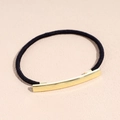 Dettaglio di un elastico per capelli nero con un elegante inserto in metallo dorato lucido - Elastico per capelli a bordo sottile Oro