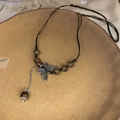 Gros plan du collier papillon en céramique avec perles brunes et glands de soie - Collier Papillon Perlé Café Foncé