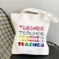 White canvas tote bag featuring four colorful rows of Teacher print on a black chair - Colorful Teacher Text