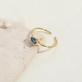 Detail eines verstellbaren 14K vergoldeten Rings mit einem birnenförmigen blauen Edelstein - Königsblau