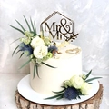 Detail of golden Mr & Mrs acrylic topper on a white floral wedding cake with wood base - Gold Hexagonal Frame MR&MRS
